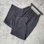 Pair of dark sweatpants showing elastic waistband and front pockets, logo patch detail.