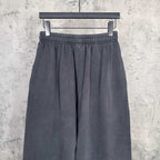 Dark pleated sweatpants with elastic waistband and loose wide-leg silhouette.