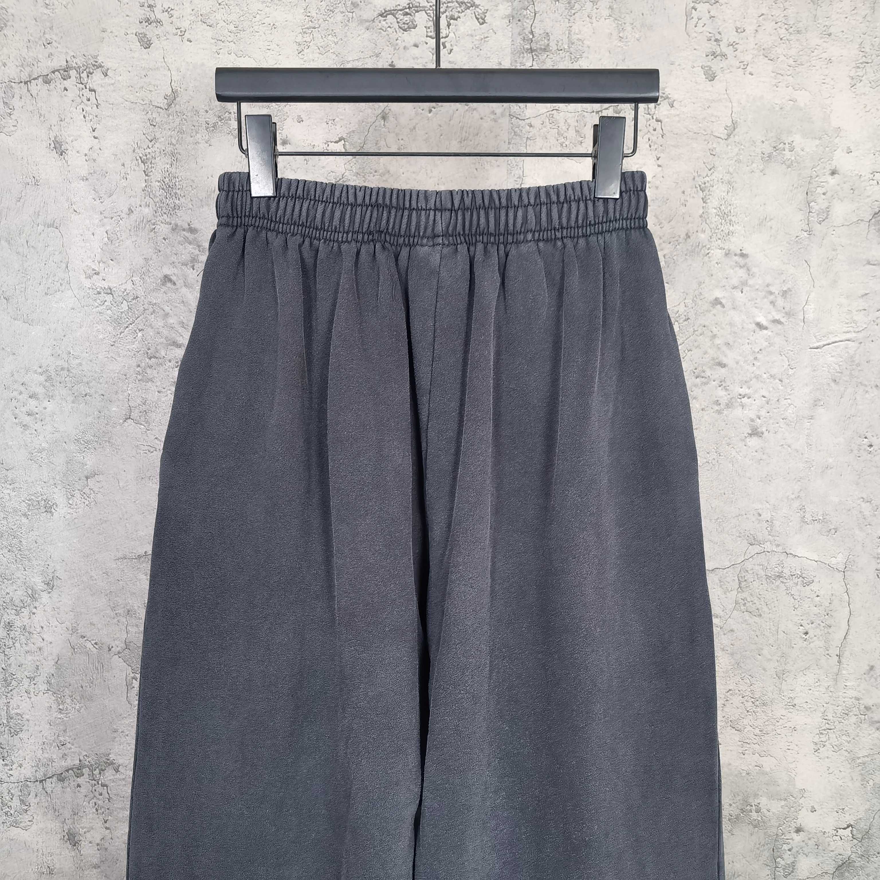 Dark pleated sweatpants with elastic waistband and loose wide-leg silhouette.