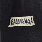 BALENCIAGA logo patch on dark fabric, white label with black lettering.