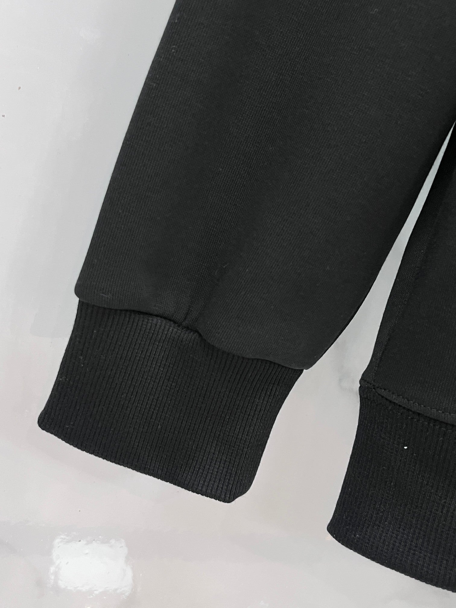 Dark/black crewneck sweatshirt sleeve with ribbed cuff and hem