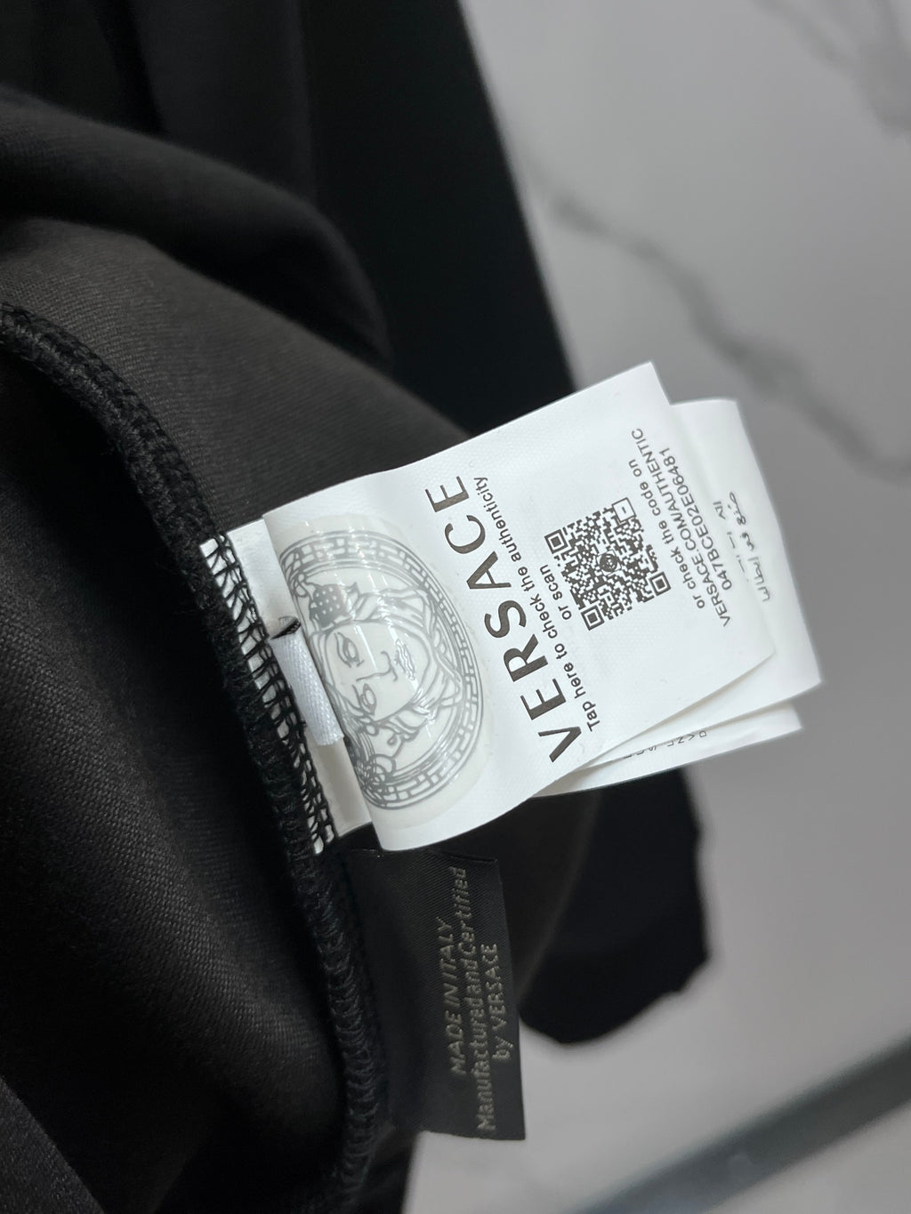 Black crewneck sweatshirt fabric close-up with white brand care label tag