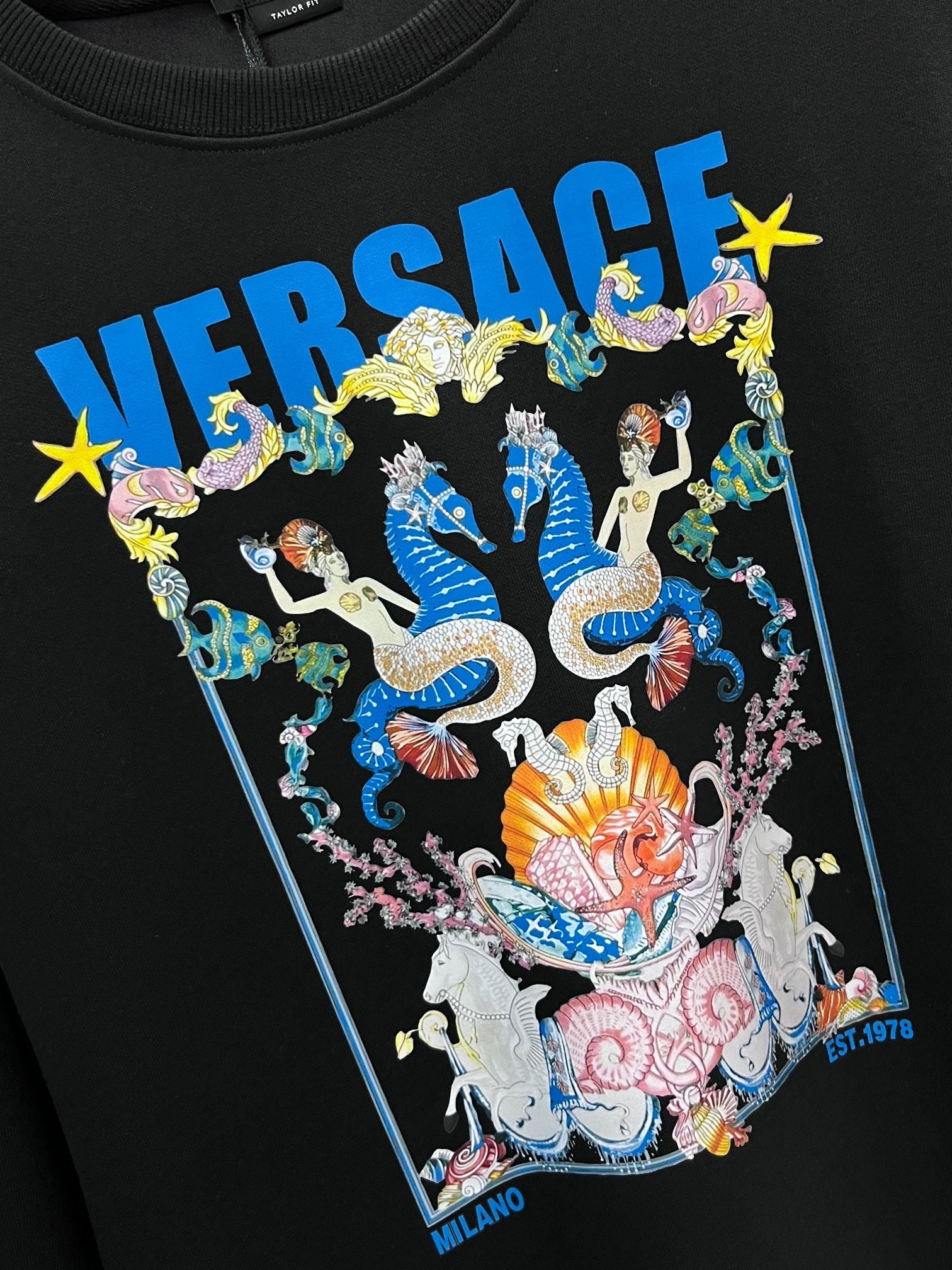 Black crewneck sweatshirt with large multicolor graphic print and blue logo text