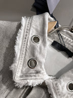 White denim strap detail with frayed edges and two round ring eyelets