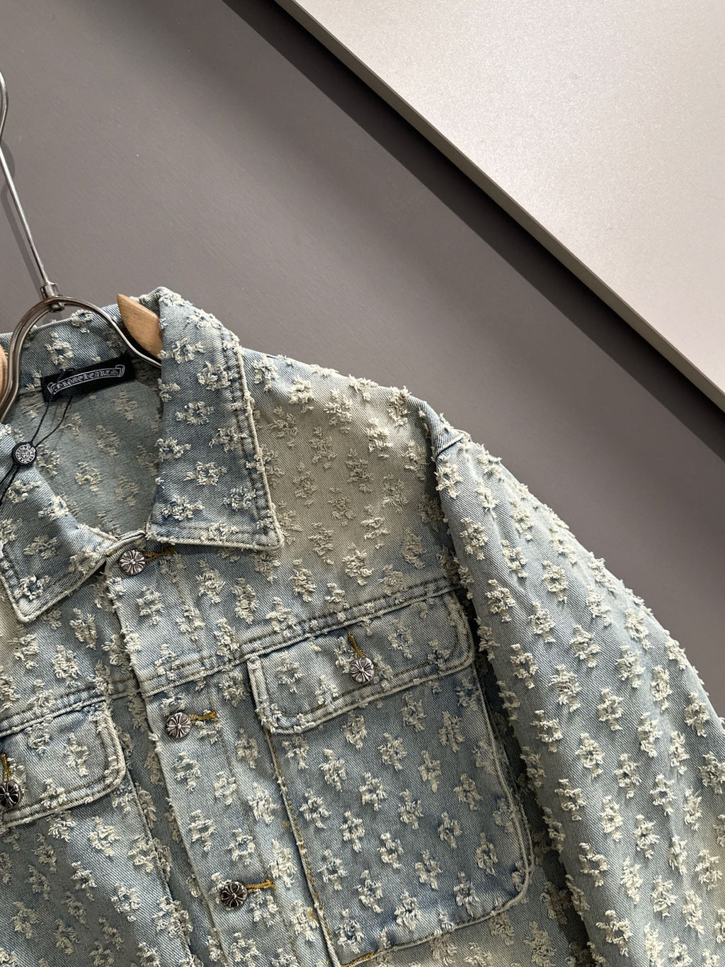 Light blue denim jacket front detail with floral embroidery, collar, and button placket