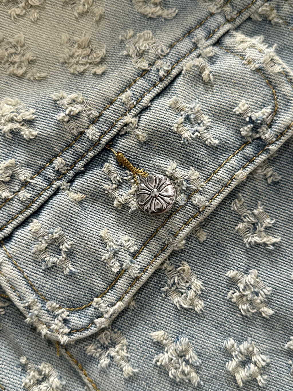 Denim jacket detail: button placket and curved pocket flaps with floral embroidery