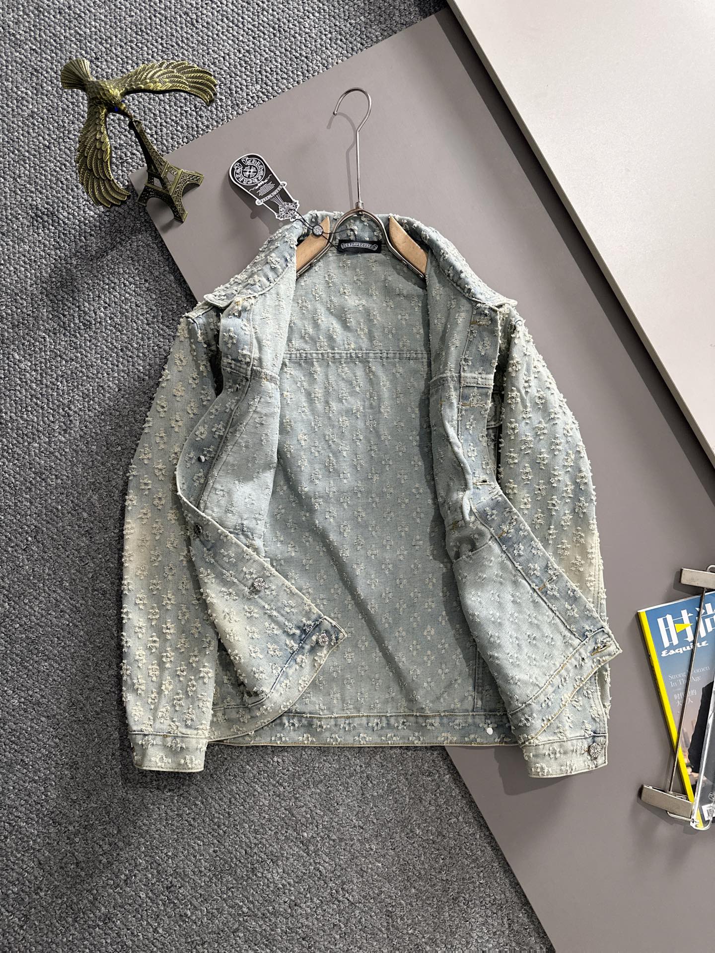 Light blue denim jacket on hanger with floral embroidery, button front, flap pockets