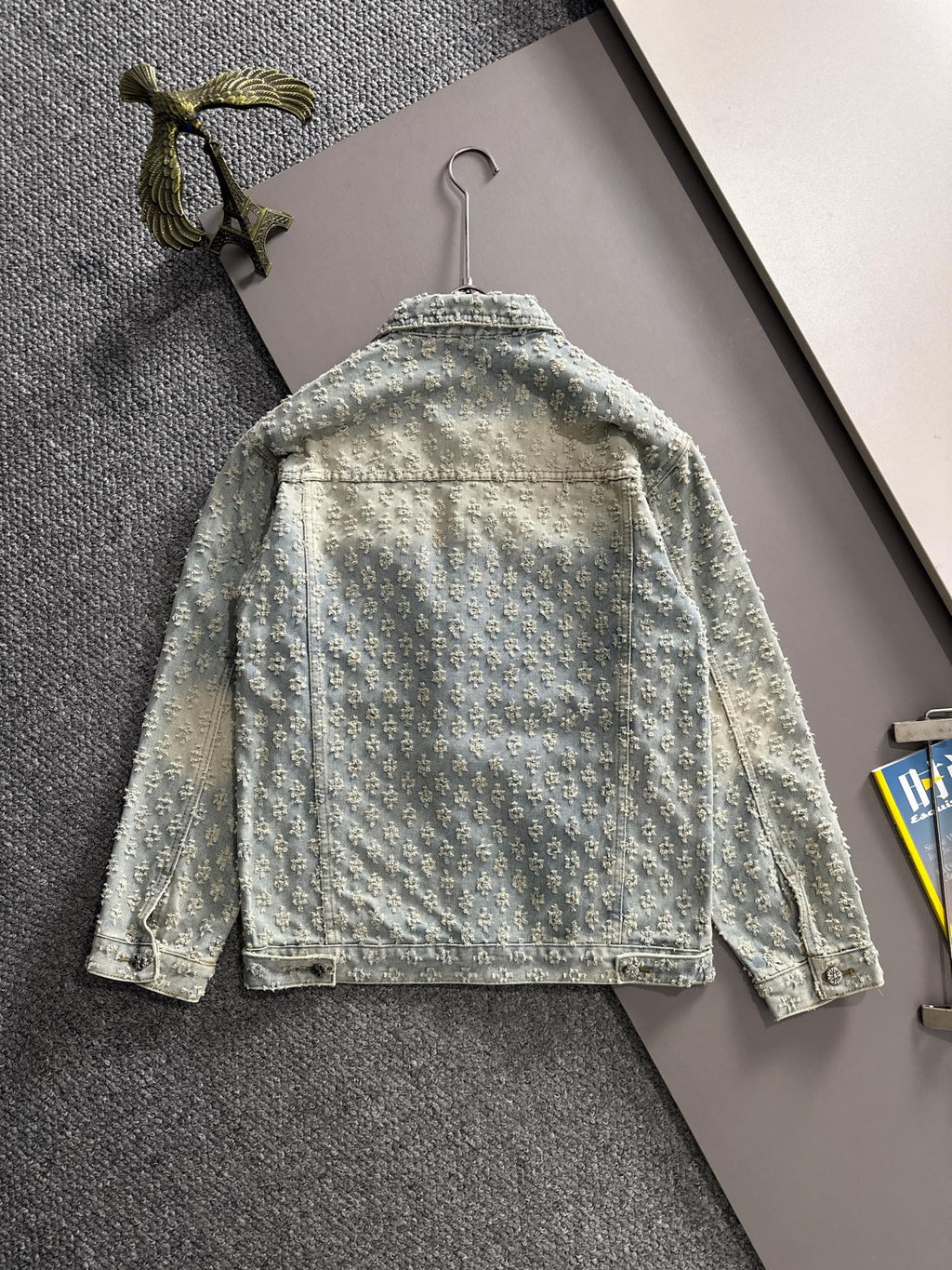 Light blue denim jacket back view with floral embroidery, yoke seam, and button closures