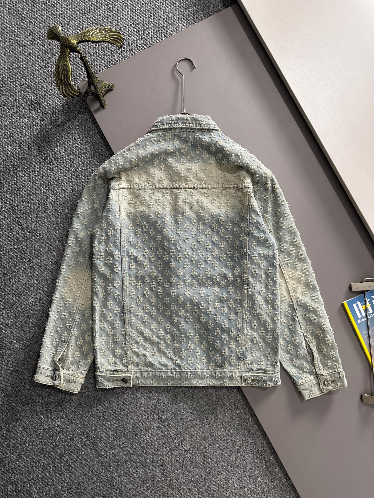 Light blue denim jacket back view with floral embroidery, yoke seam, and button closures
