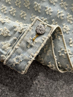 Light blue denim jacket collar detail with decorative round button and floral embroidery