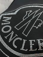 Black T-shirt close-up with rhinestone logo detail