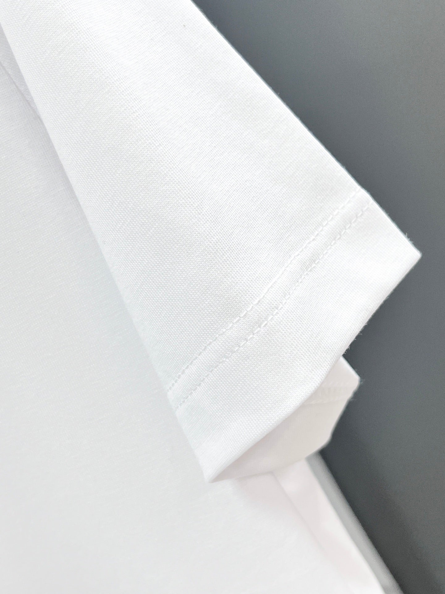 White T-shirt sleeve and hem close-up, smooth fabric texture.