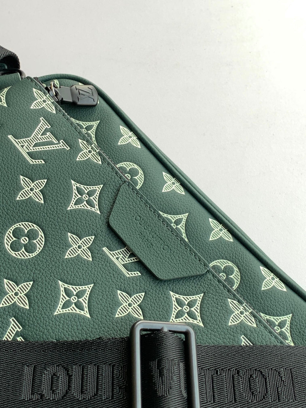 Louis Vuitton teal monogram fabric close-up with black strap detail