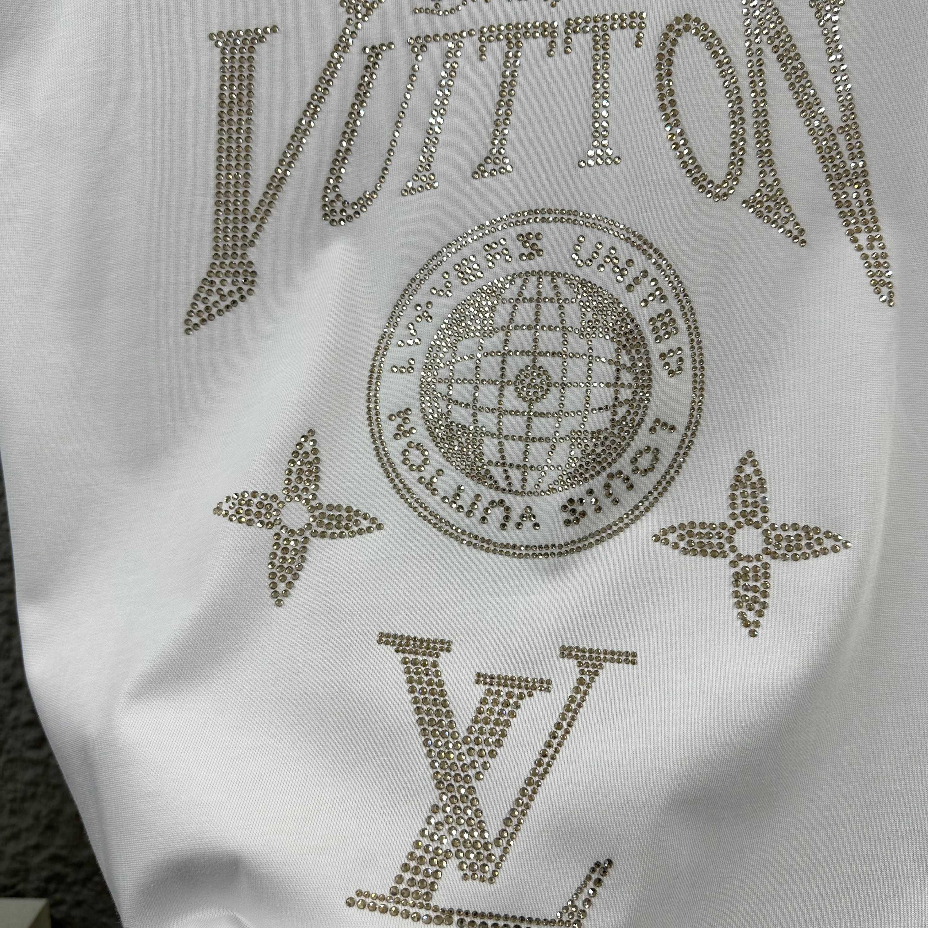 Close-up of white Louis Vuitton T-shirt rhinestone LV lettering and globe emblem