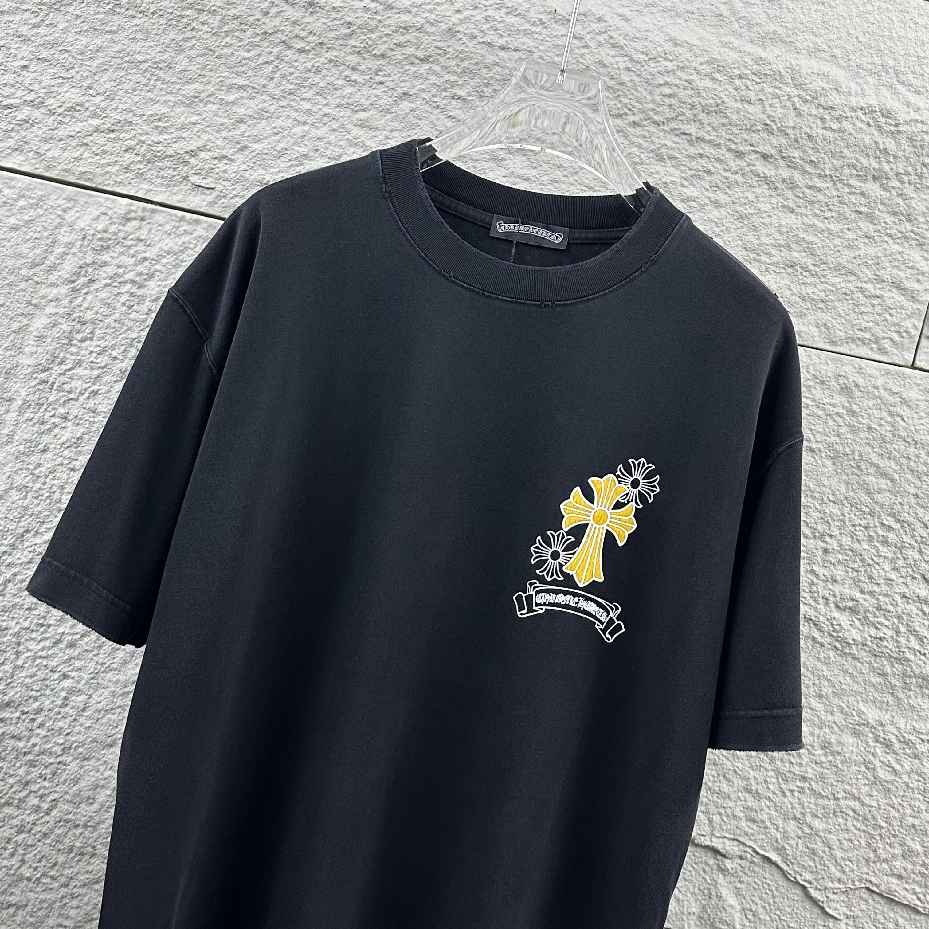 Dark T-shirt with small cross-flower graphic on left chest