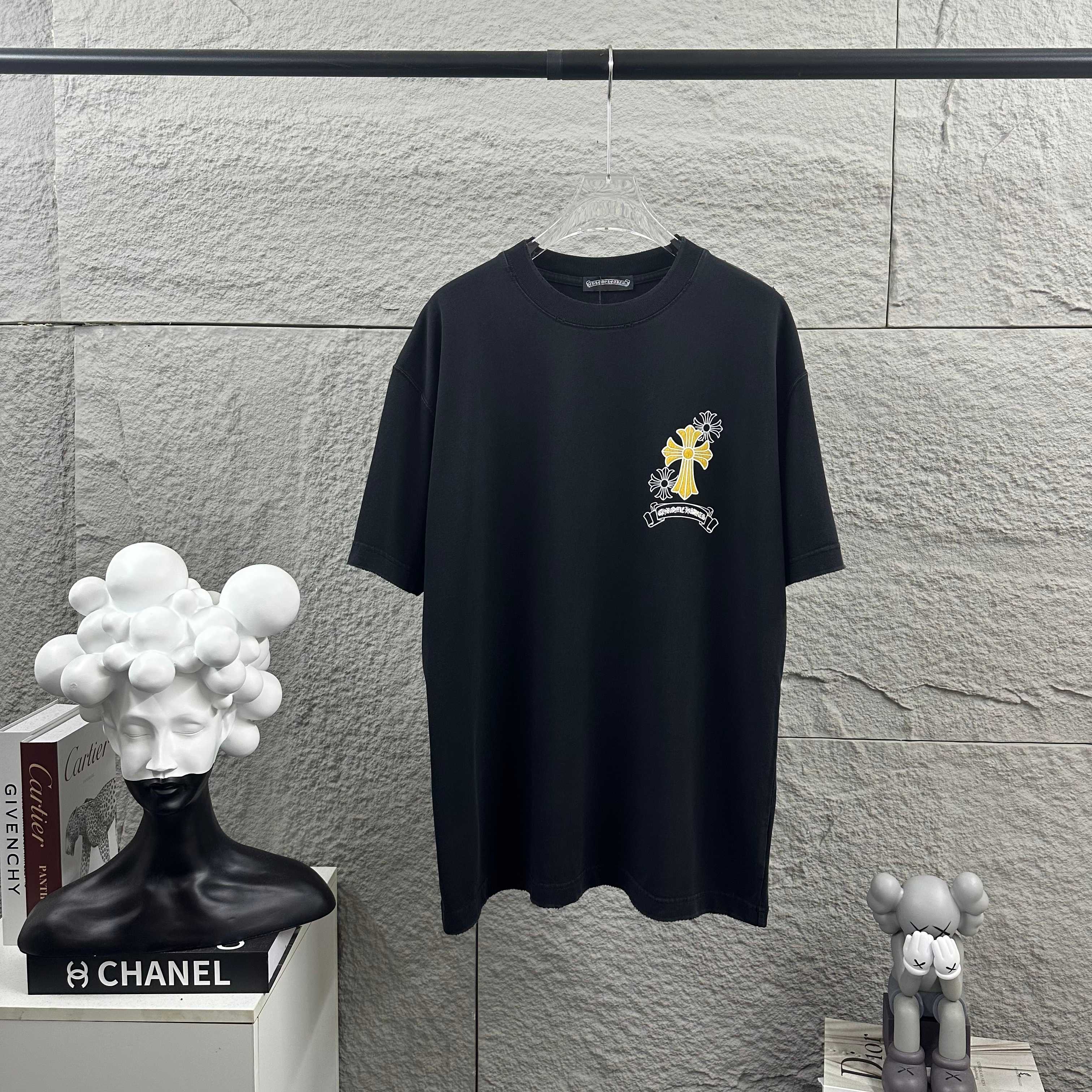 Dark T-shirt with small cross-flower logo graphic at chest