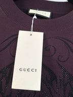 Gucci crewneck sweater close-up with white price tag and dark plum front graphic