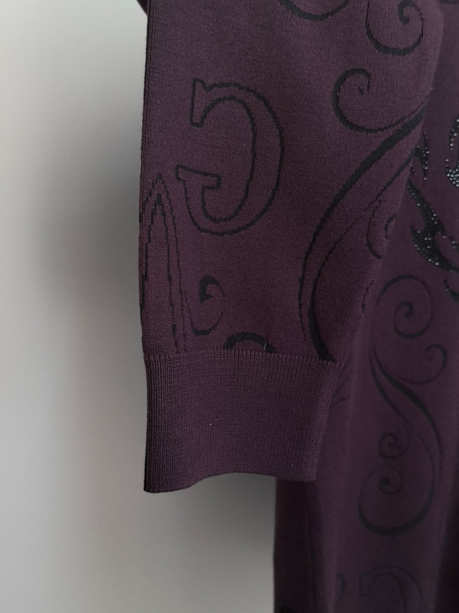 Crewneck sweater hem and side in dark plum with subtle raised swirl pattern