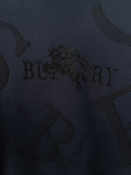 Burberry long-sleeve sweater close-up of dark navy knit with embellished logo detail.