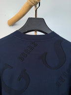 Burberry long-sleeve sweater back close-up with “B” logo and crew neckline.