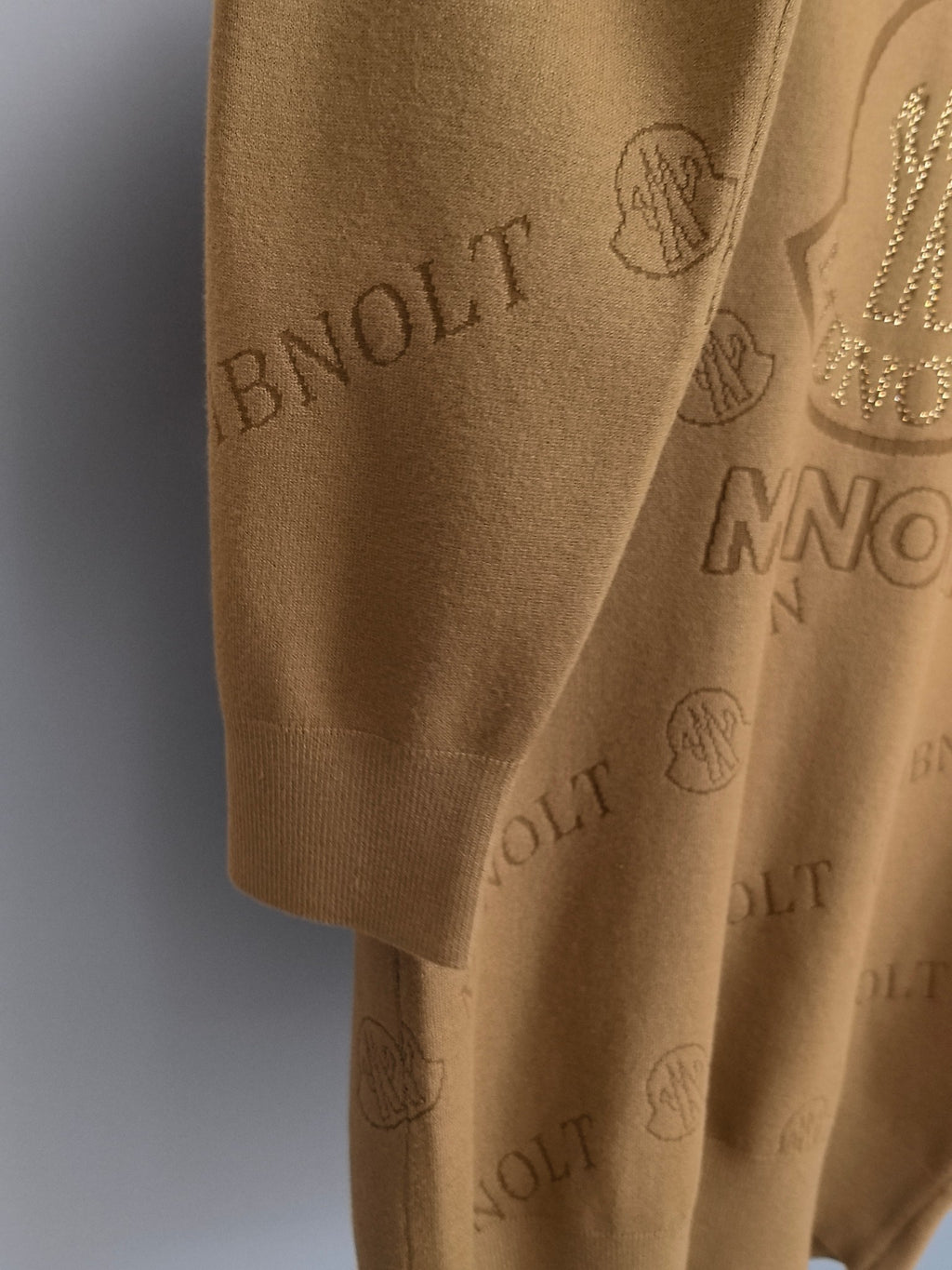 Tan knit sweater close-up of hem and allover Moncler logo pattern