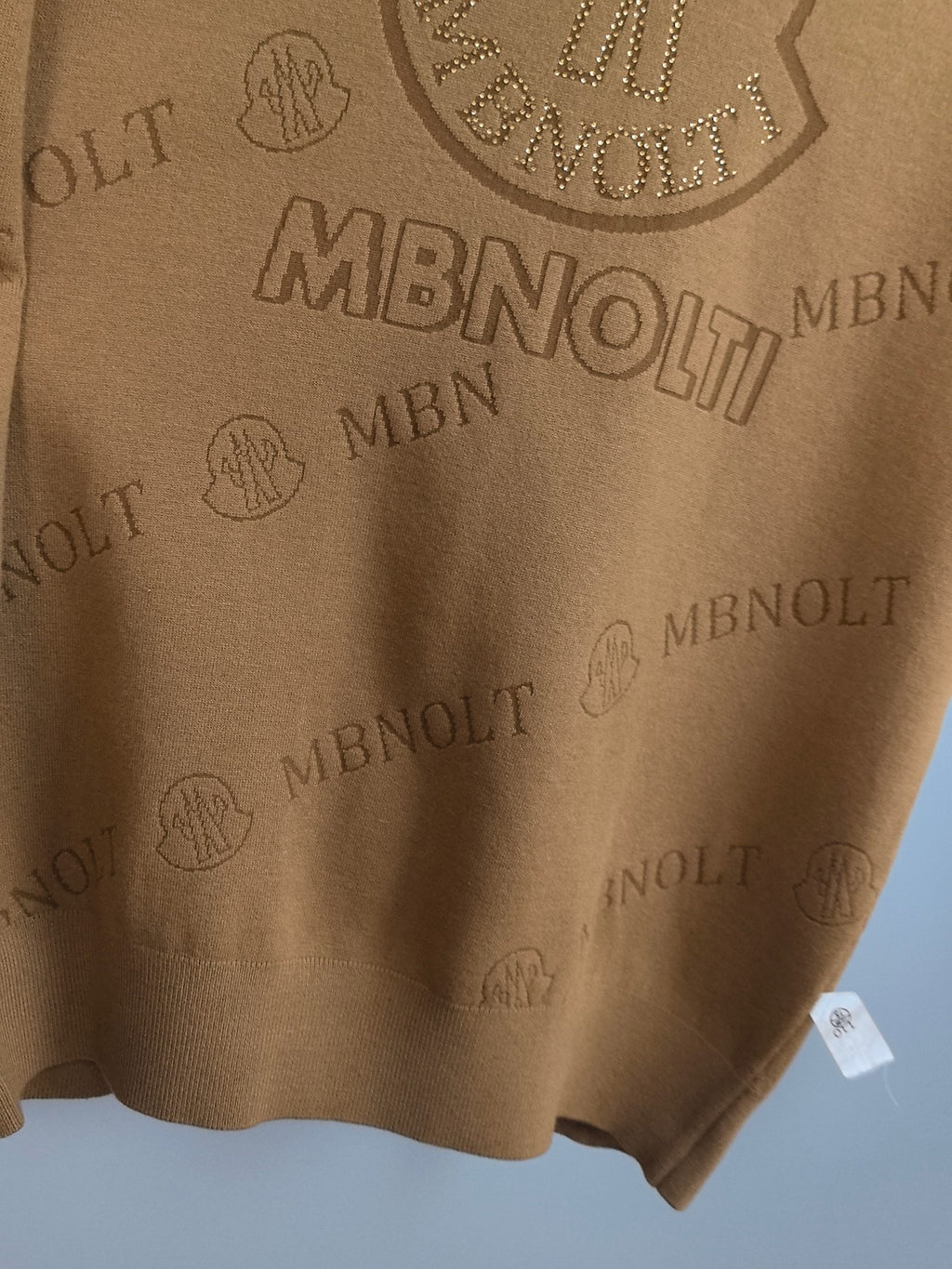 Tan knit sweater bottom hem with small attached label