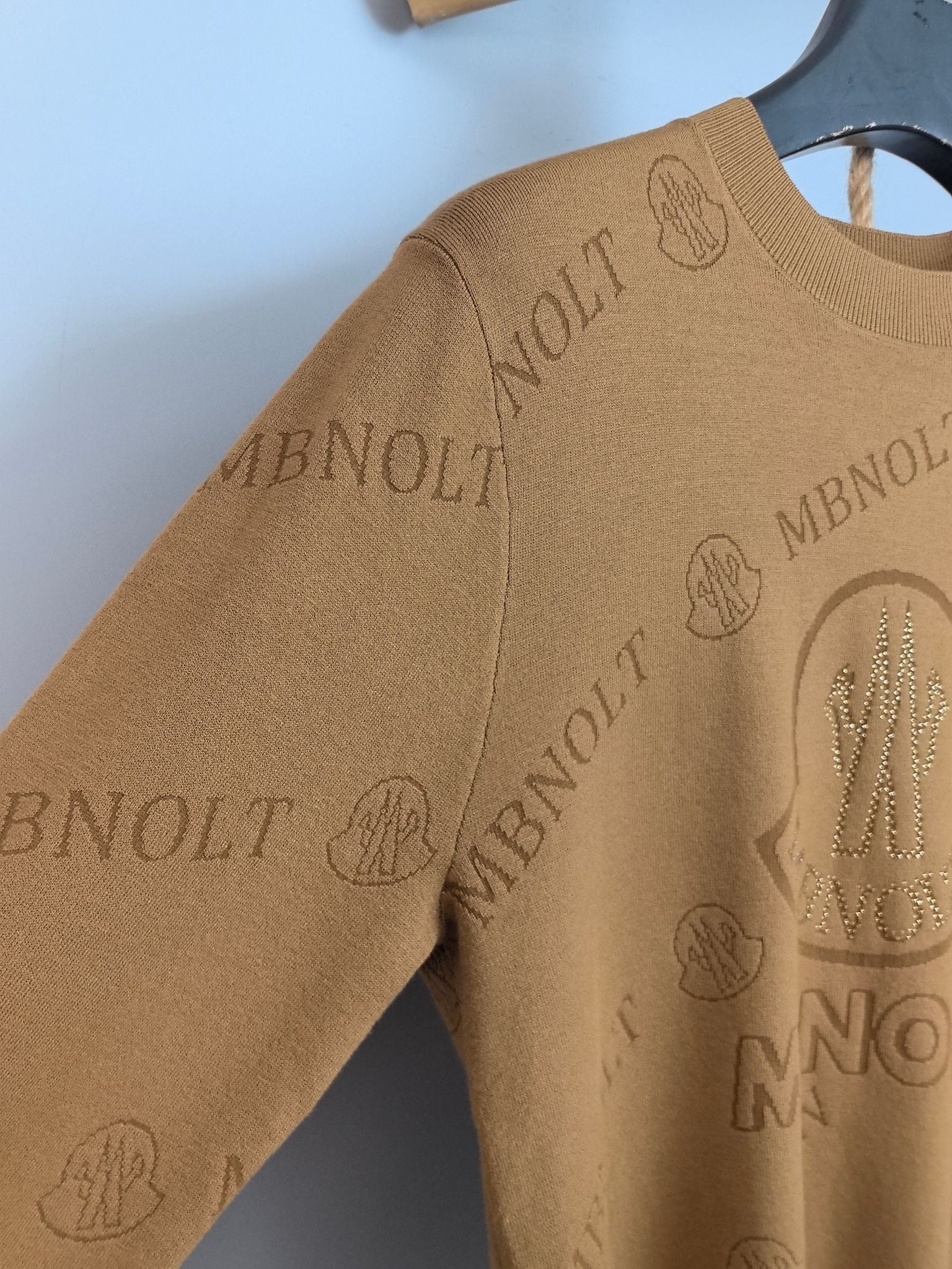 Tan knit sweater sleeve and side with allover Moncler logo pattern