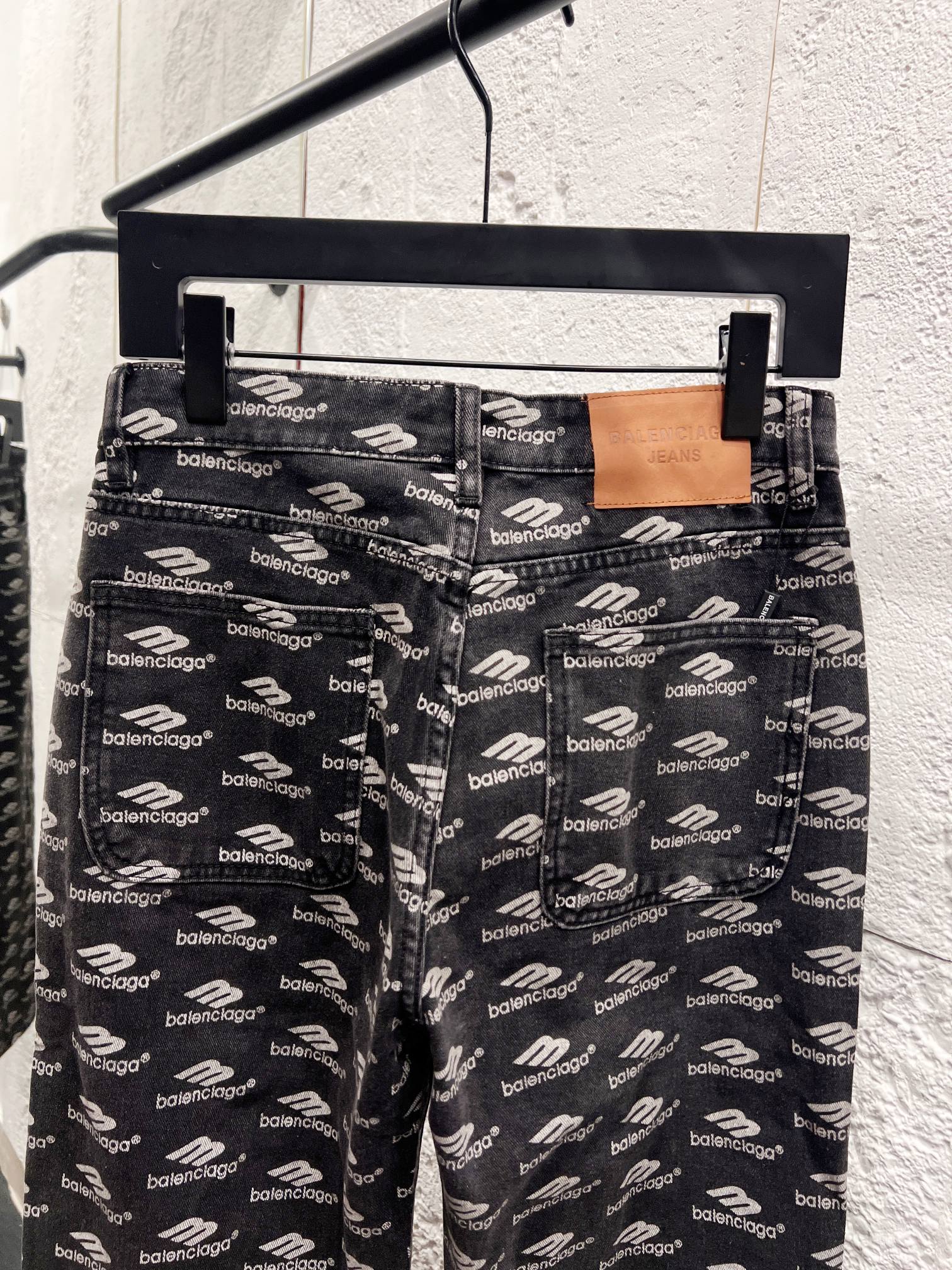 Balenciaga logo-print denim pants on hanger, relaxed straight-leg fit