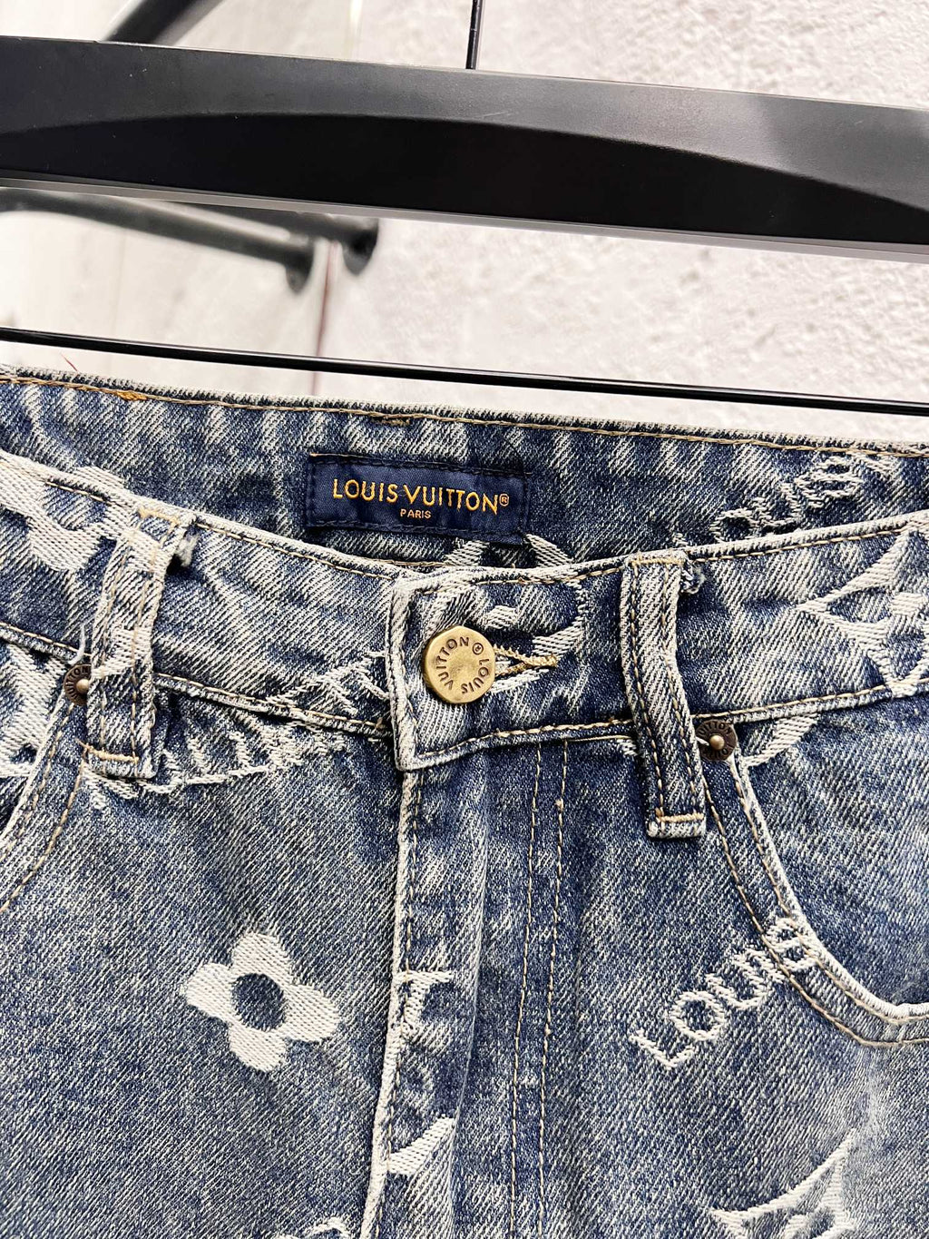 Waistband close-up with Louis Vuitton logo patch on light blue denim