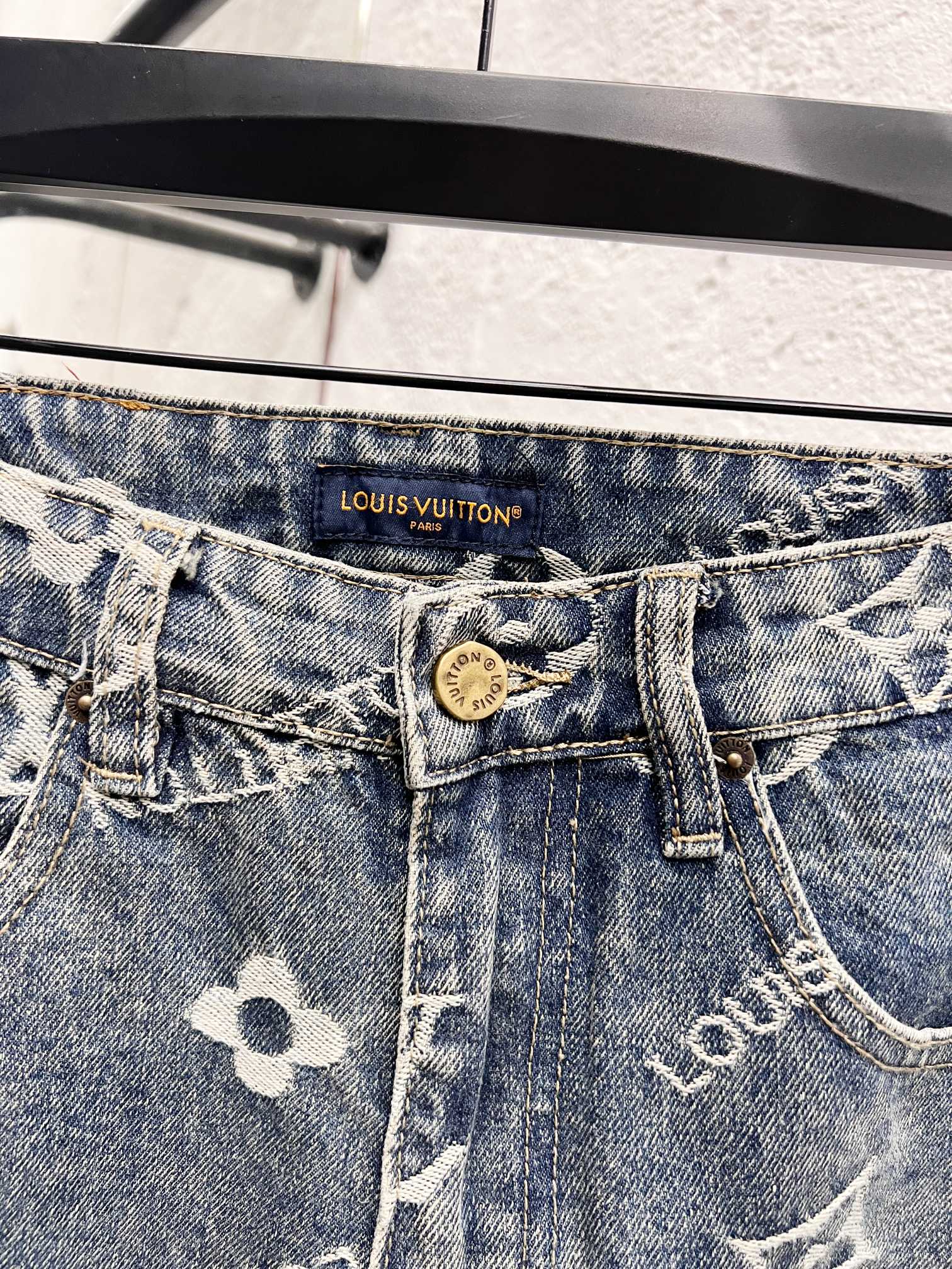Waistband close-up with Louis Vuitton logo patch on light blue denim