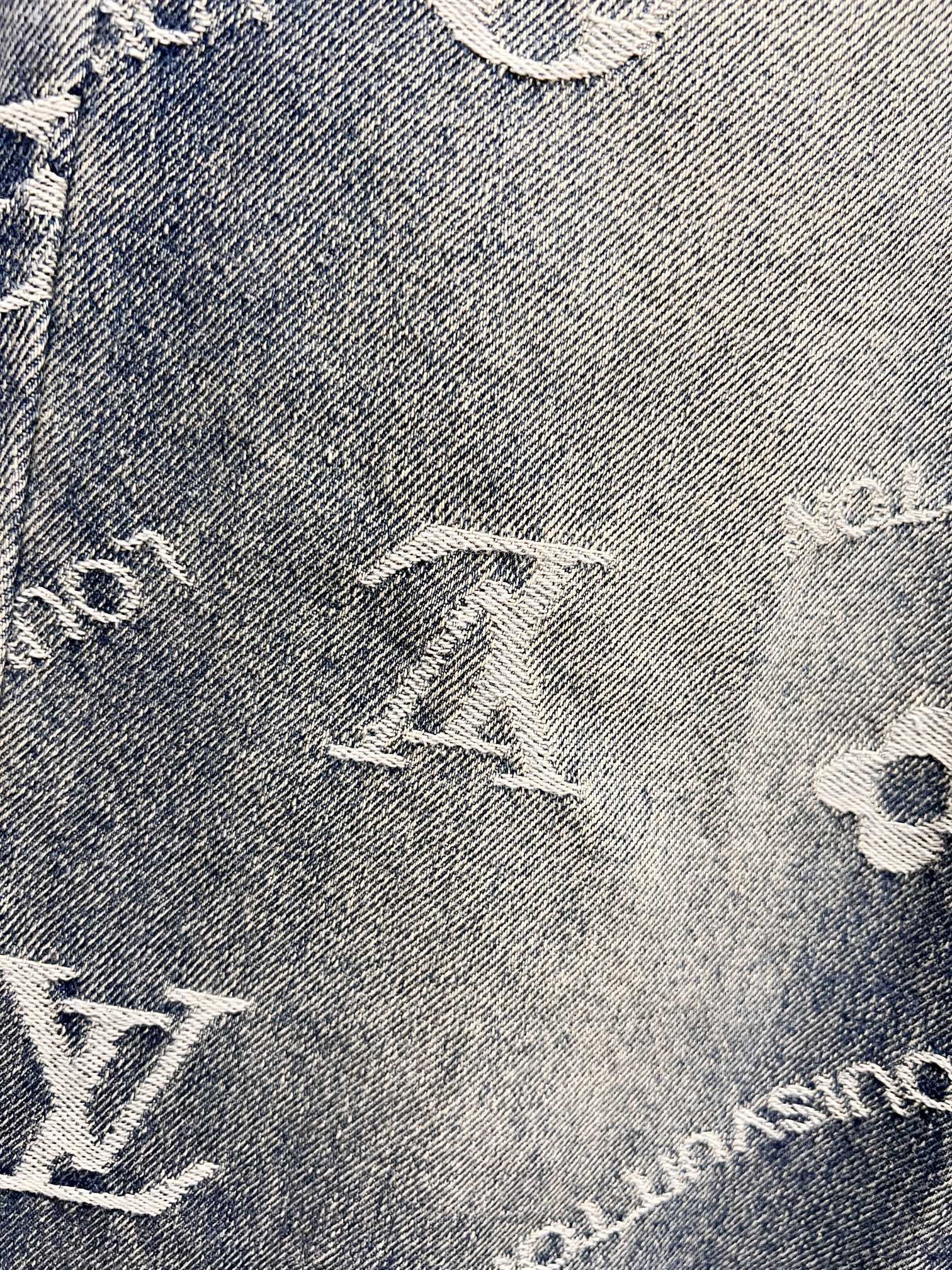 Close-up of blue denim fabric with white Louis Vuitton monogram motifs