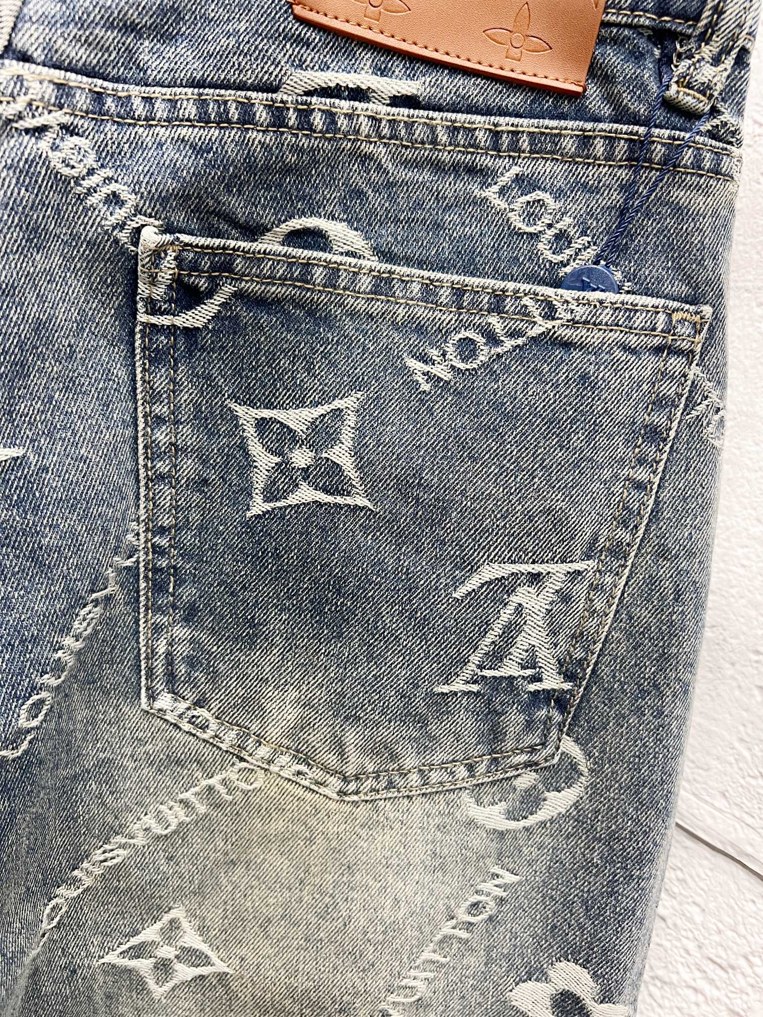 Back pocket close-up with white Louis Vuitton star and letter motifs on denim