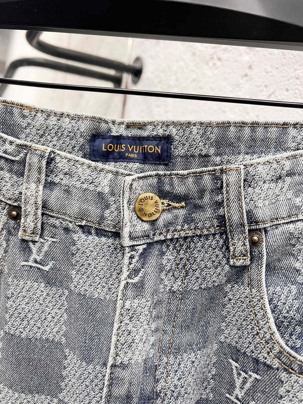 Louis Vuitton monogram jeans waistband close-up with logo patch and button fly