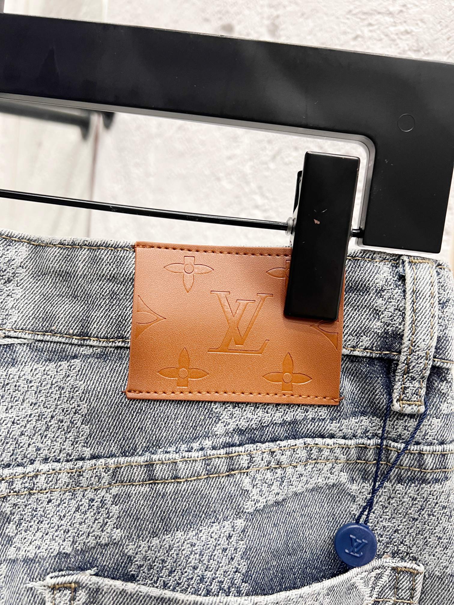 Louis Vuitton monogram jeans front pocket area with brown leather logo tab