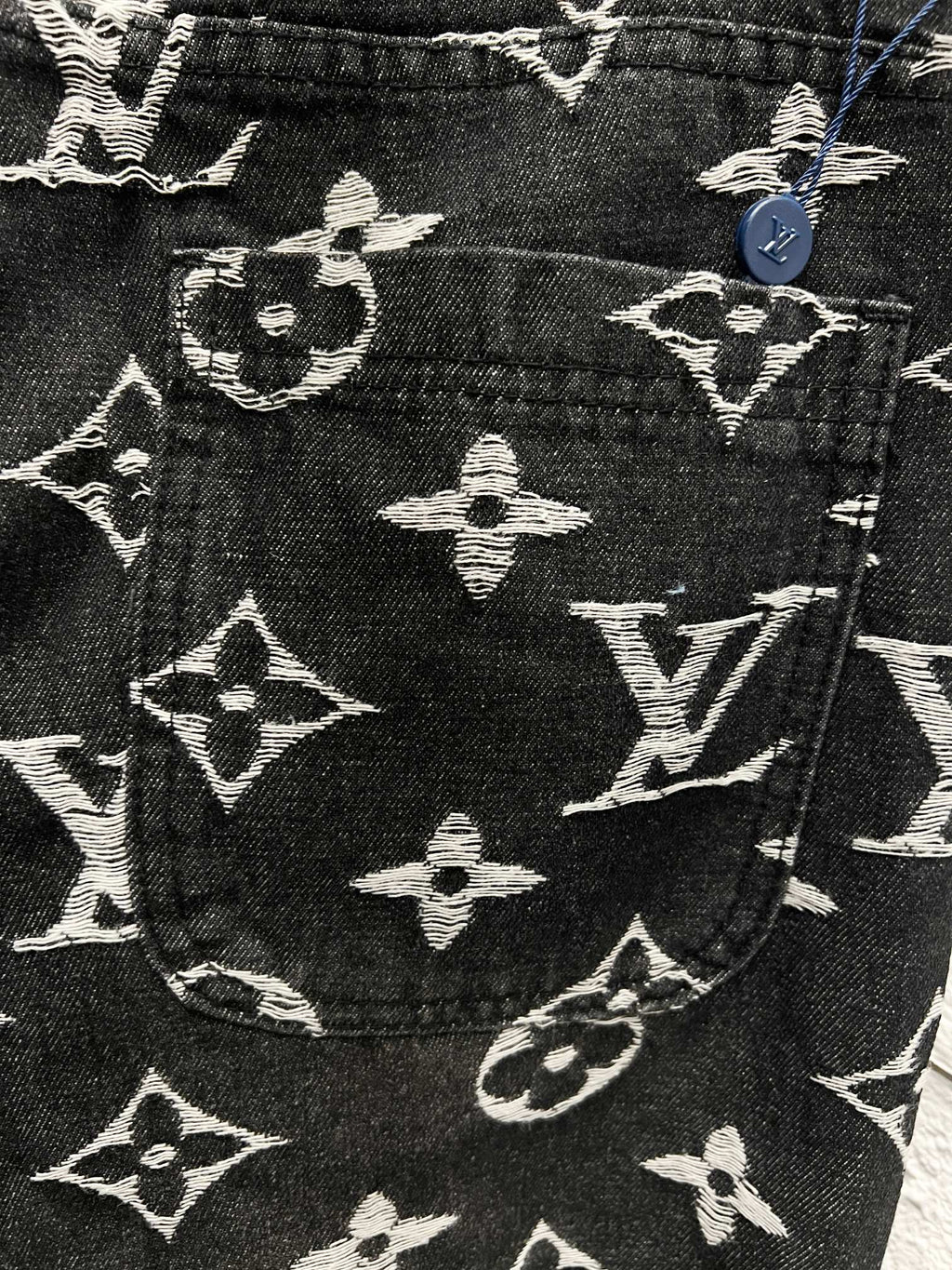 Louis Vuitton monogram print pants front detail, dark fabric with white scattered symbols