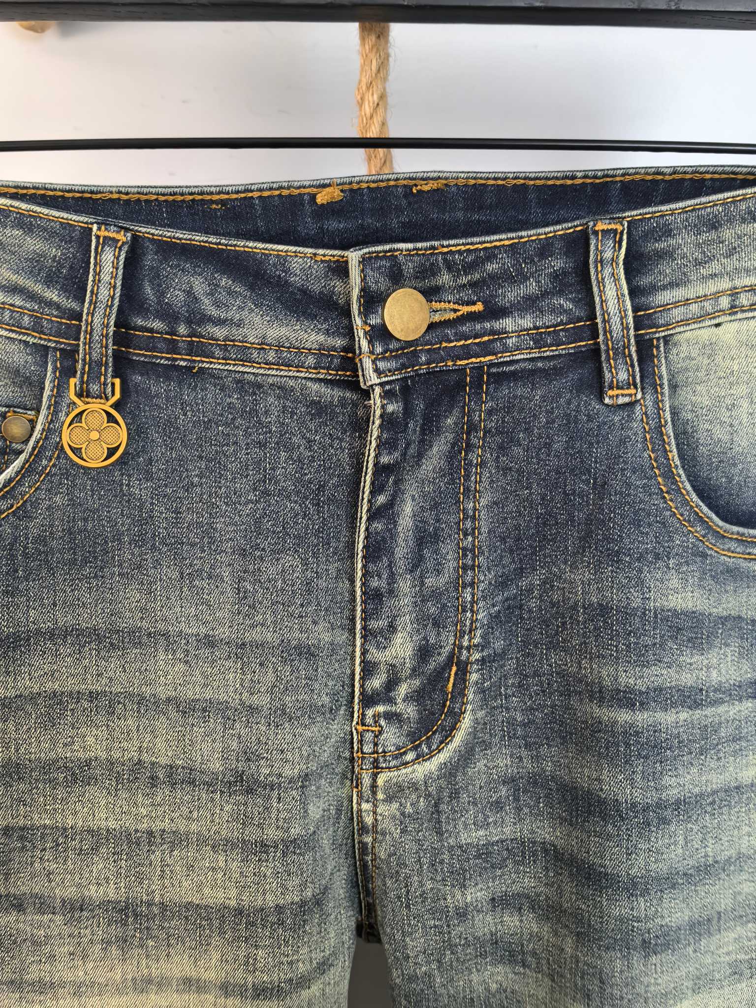 Denim waistband with gold-tone button and stitched seams, close-up