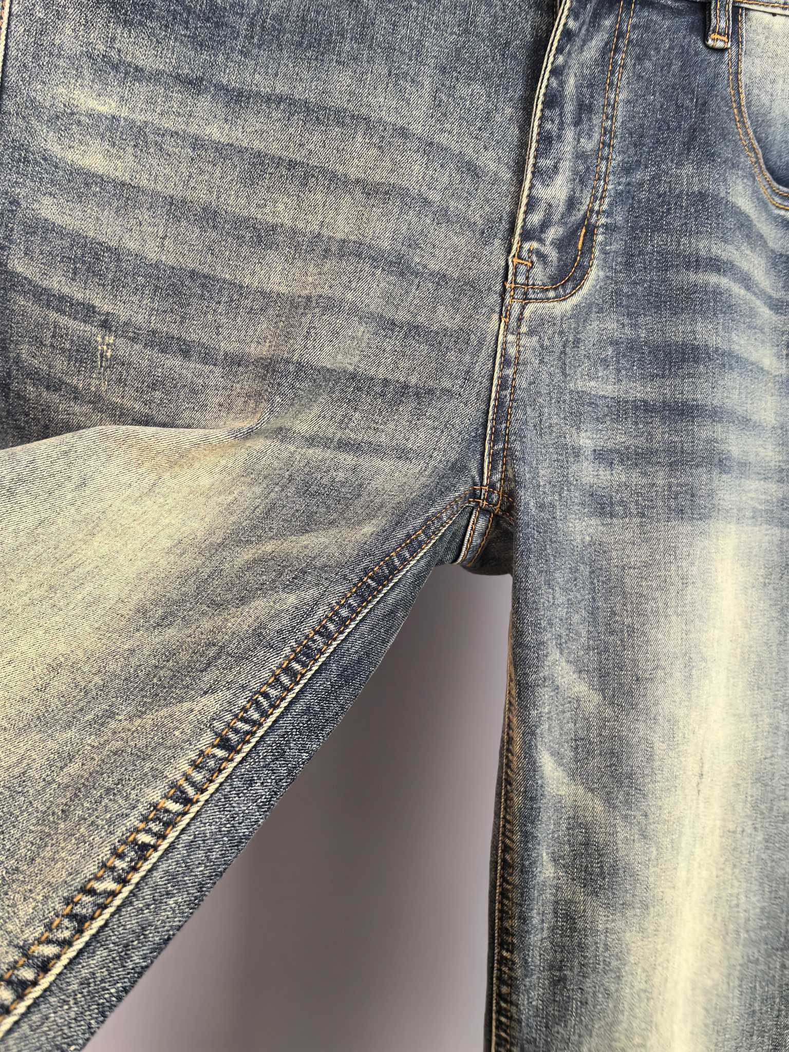 Denim pants with contrast-stitched seam and raw edge hem, close-up