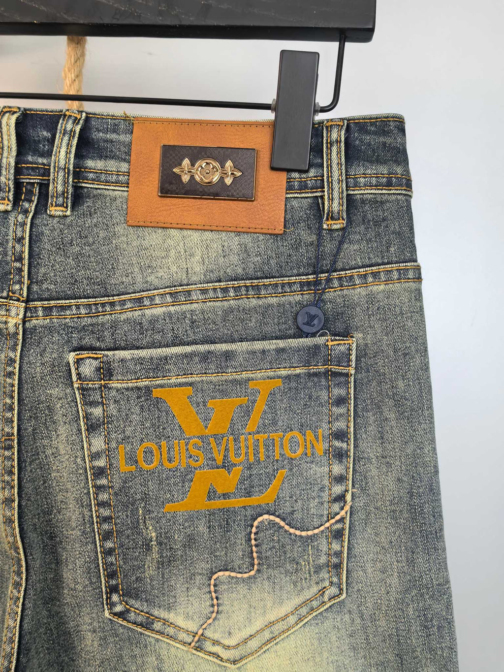 Denim pants with leather waistband patch and large printed pocket logo, back view