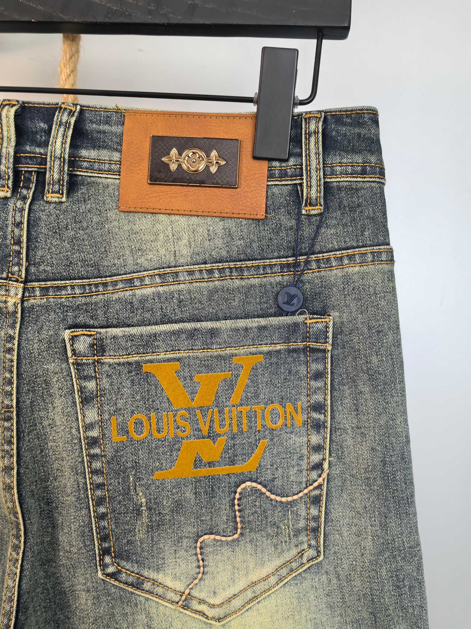Denim pants with leather waistband patch and large printed pocket logo, back view