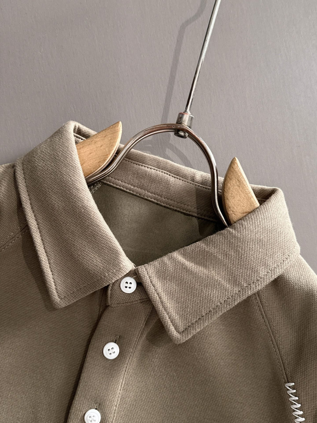Beige long-sleeve polo with pointed collar, button front, and ribbed cuffs