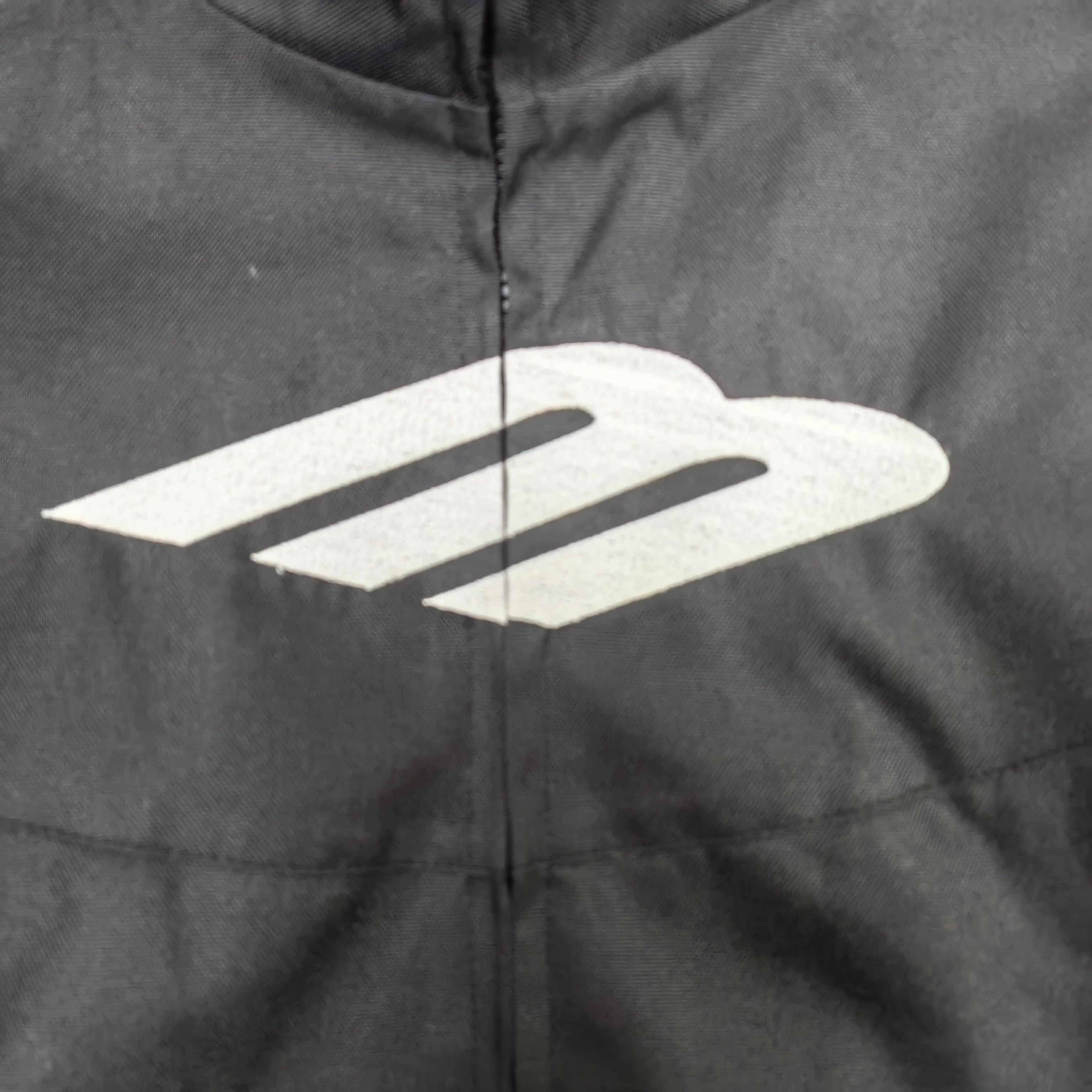Black jacket close-up with large white Balenciaga emblem over the center zipper