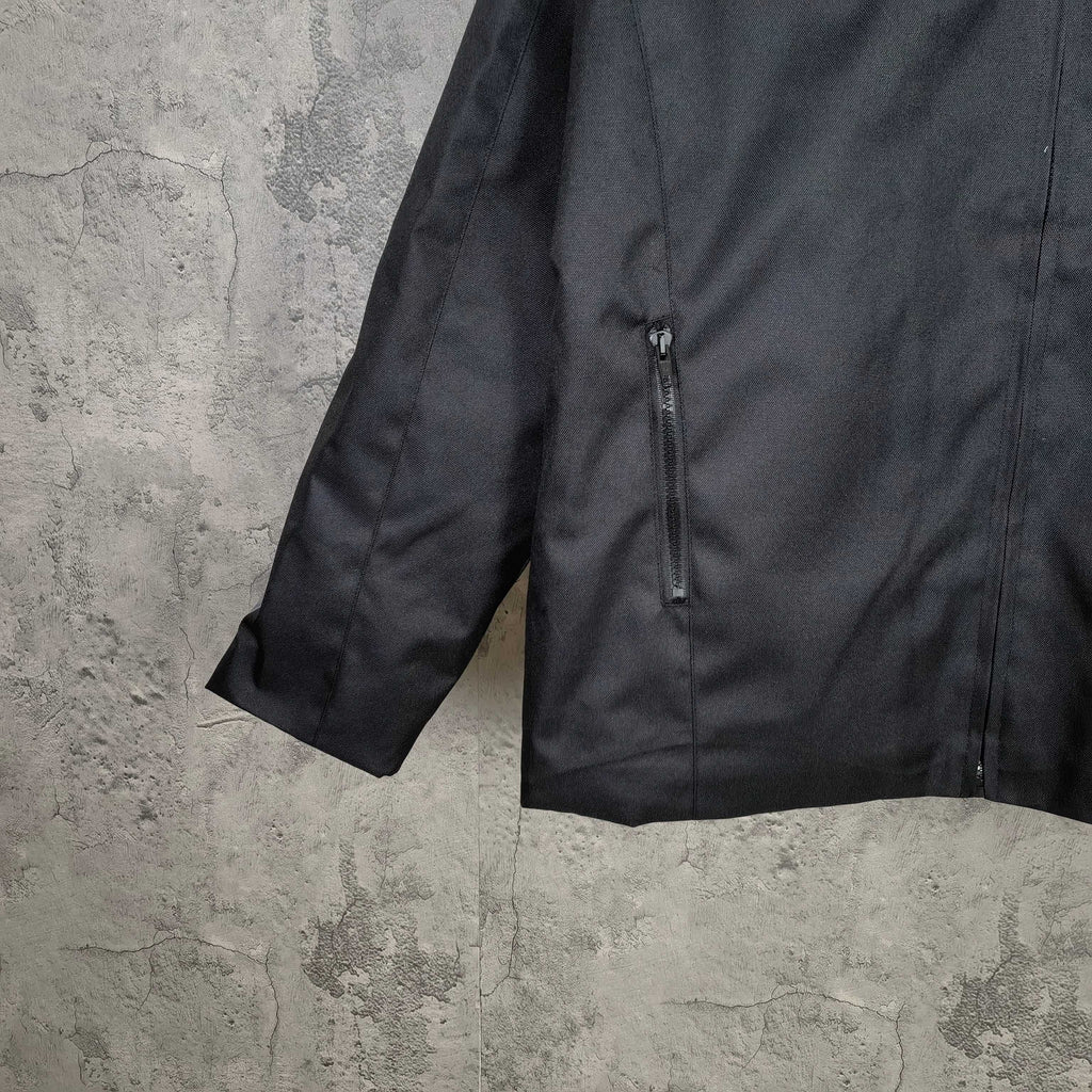 Black jacket close-up showing front zipper and short sleeve hem with stitching