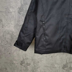 Black jacket close-up showing front zipper and short sleeve hem with stitching