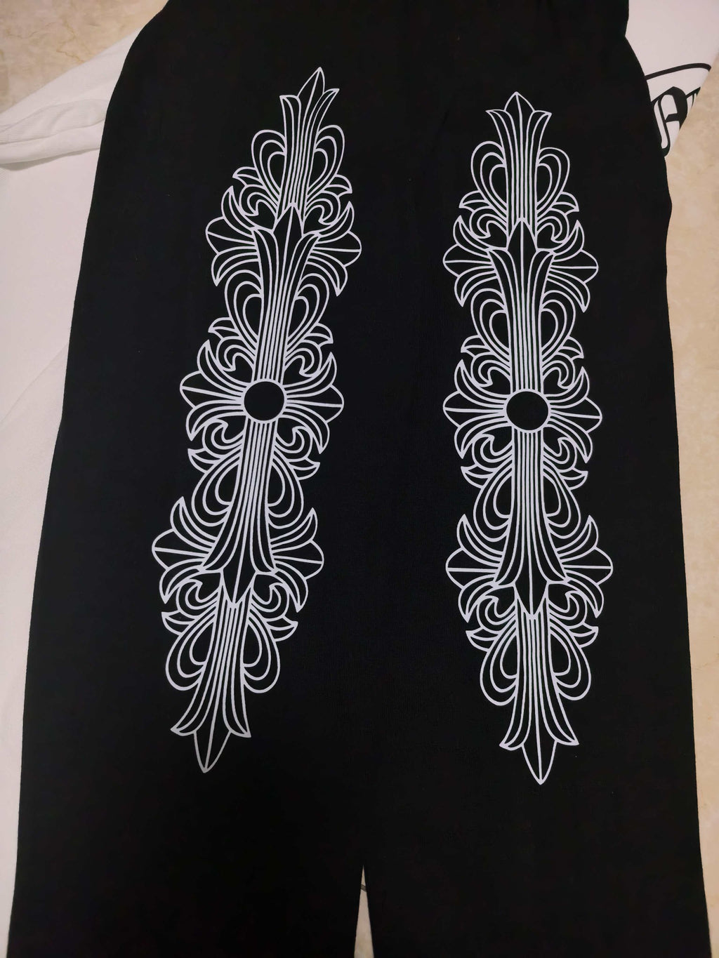 Black pants with white ornamental cross designs on front legs