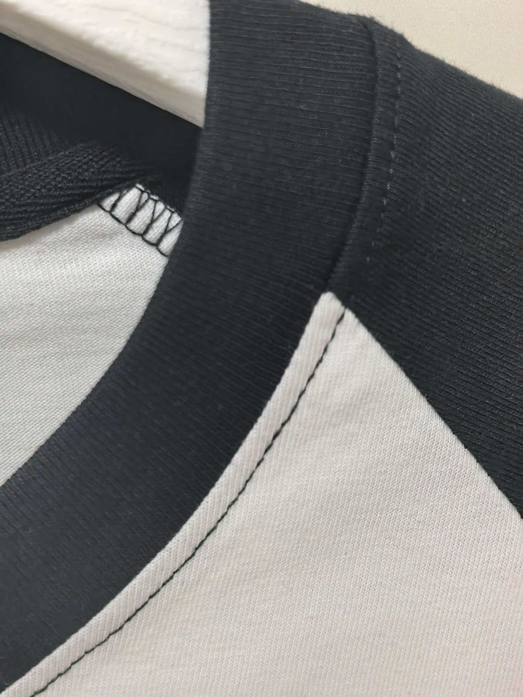 Black raglan sleeve seam with ribbed knit collar edge on a white shirt