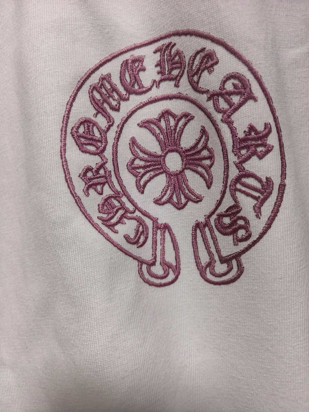 White long-sleeve T-shirt with red circular cross emblem close-up