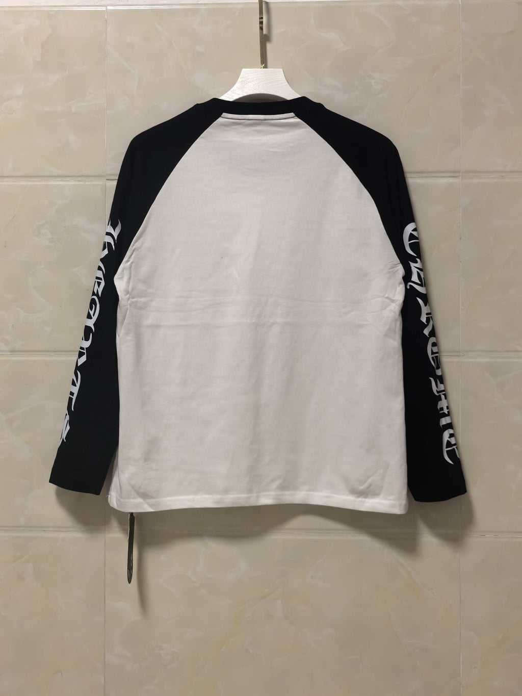 Long-sleeve raglan shirt, back view with white body, black sleeves, and sleeve text.