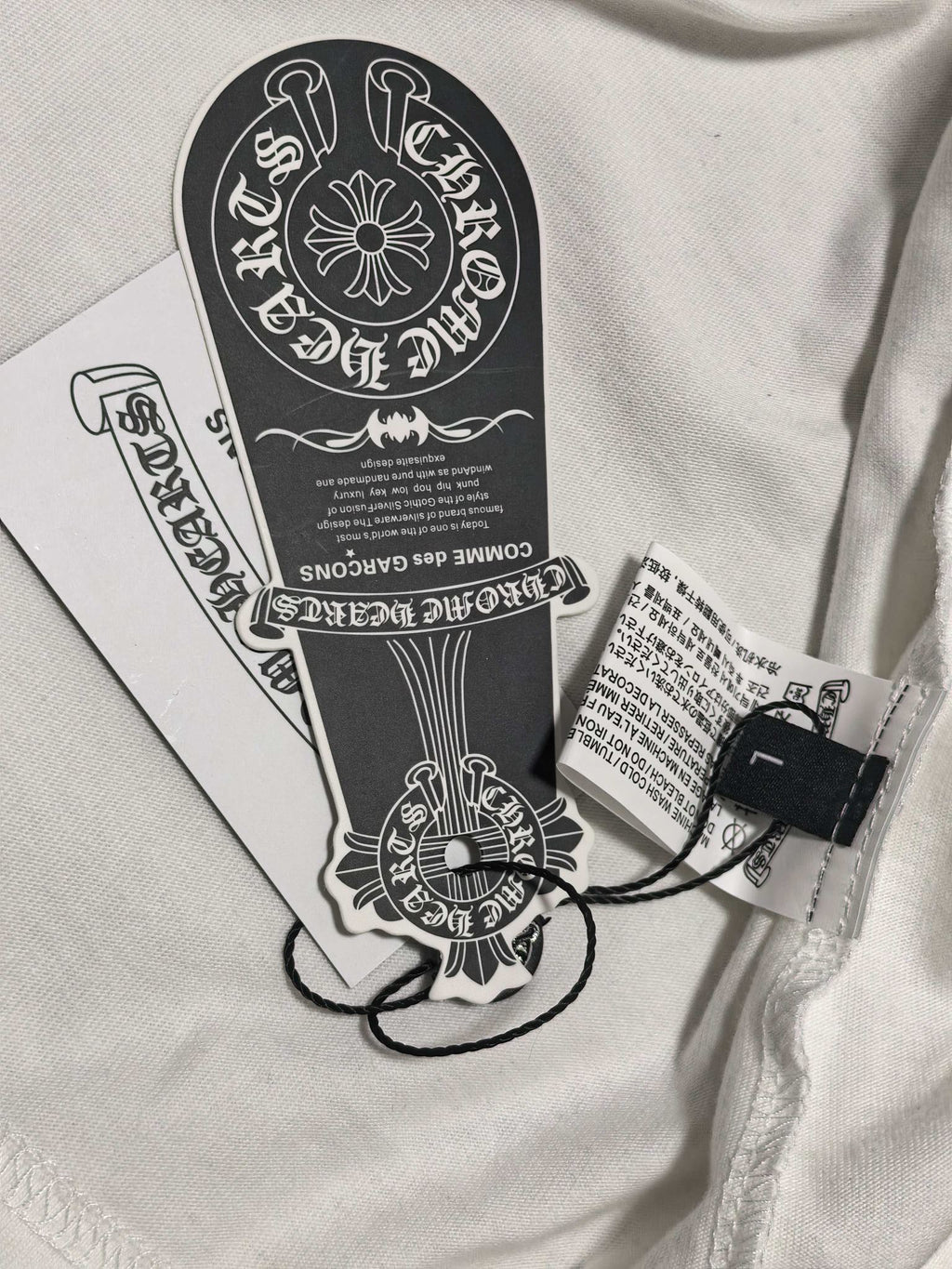 White long-sleeve T-shirt with attached black hang tag near collar