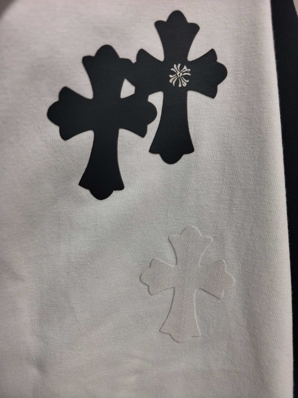 Long-sleeve T-shirt graphic, black cross and floral shapes on light fabric