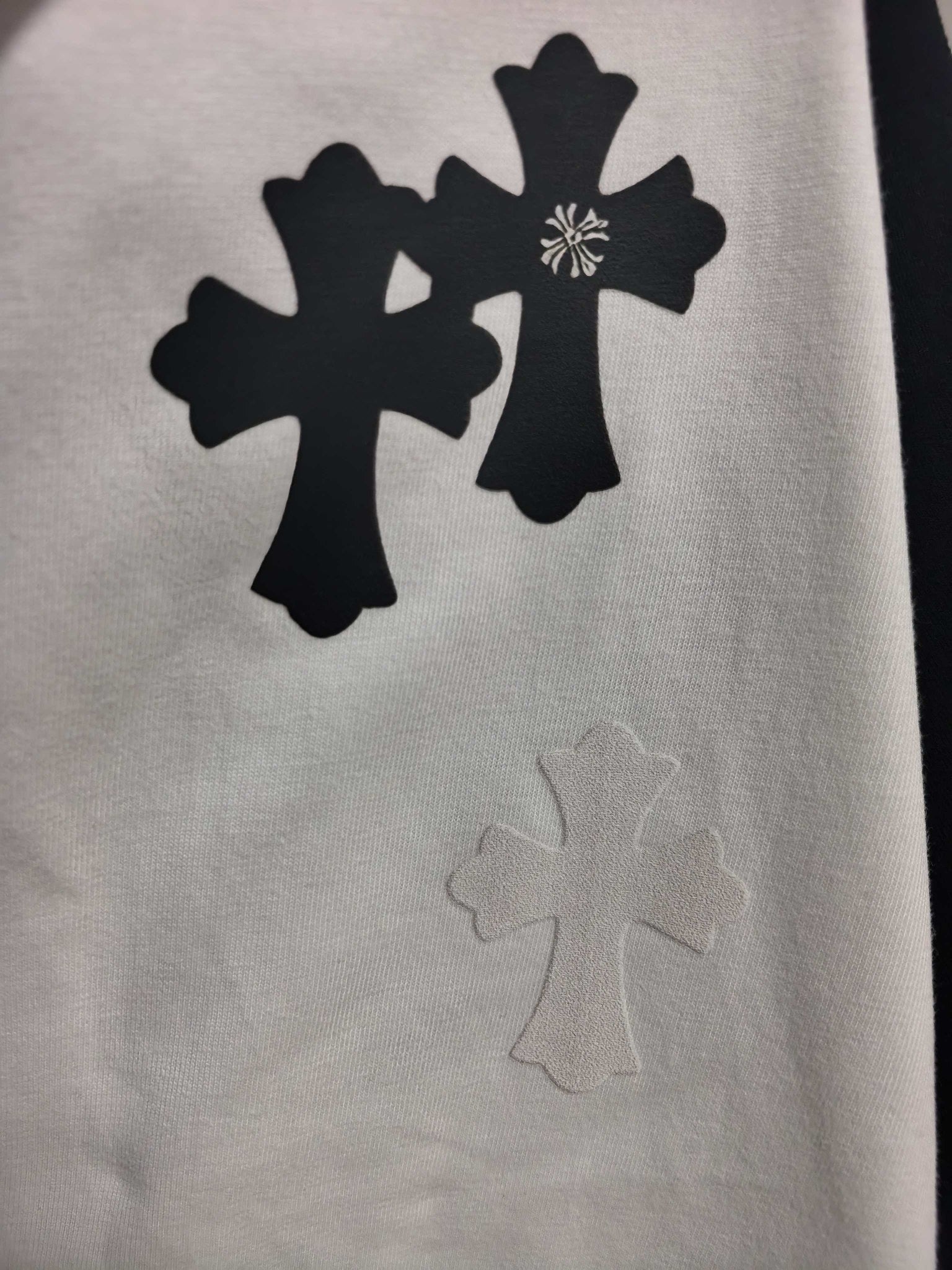 White long-sleeve T-shirt with black cross and floral emblem print